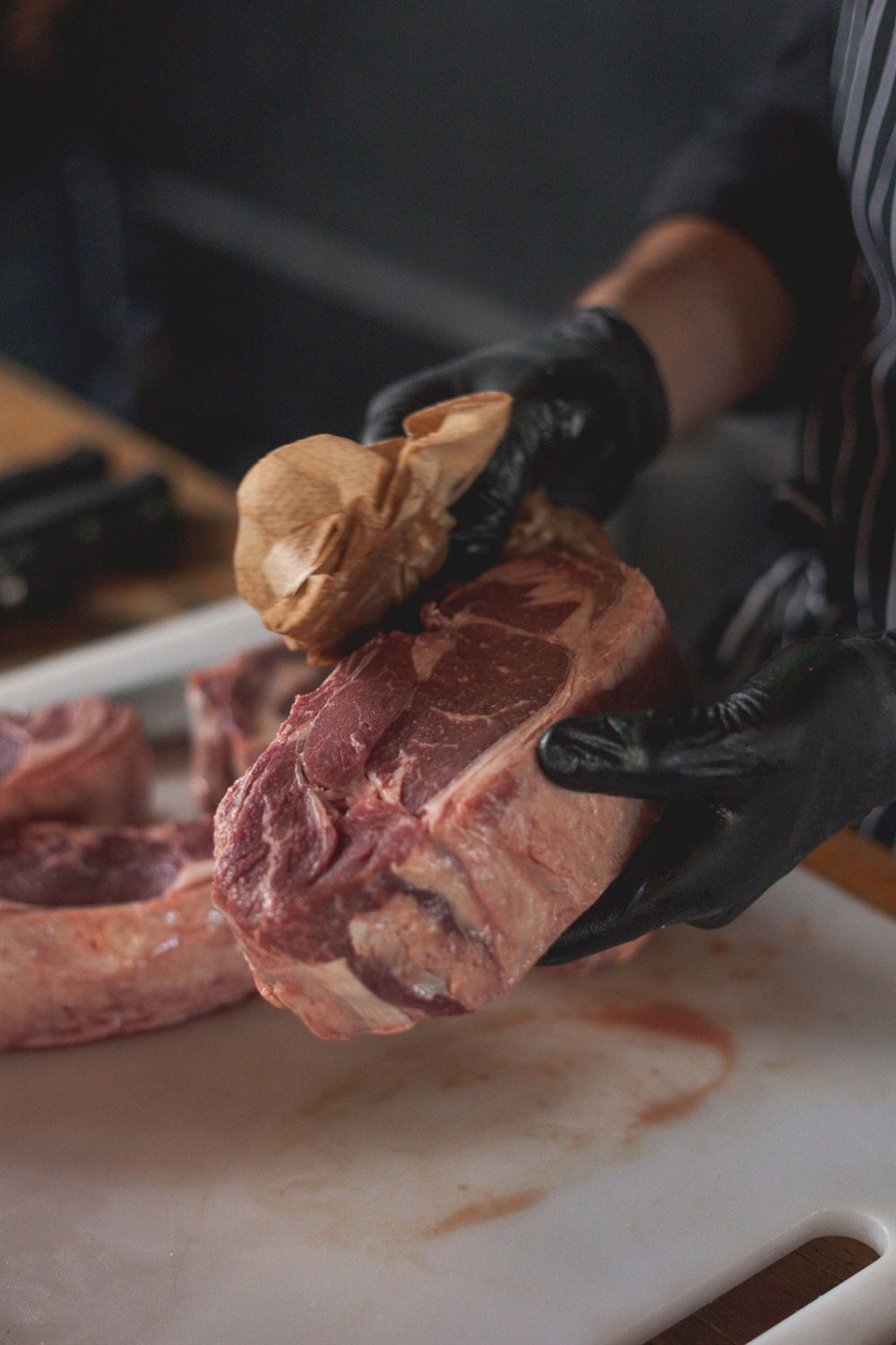 Un boucher manipule une belle pièce de bœuf crue sur une planche à découper