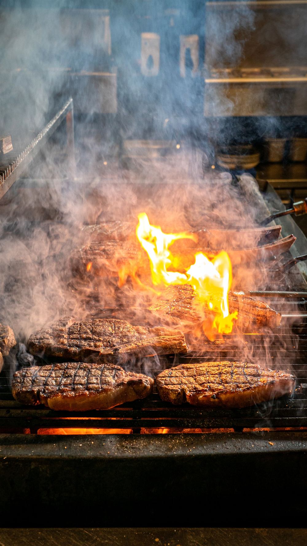 Pièces de viande sur la grille, flammes et fumée