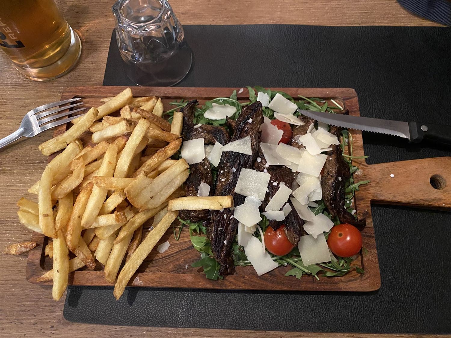 Planche de viande avec roquette, copeaux de parmesan et frites maison