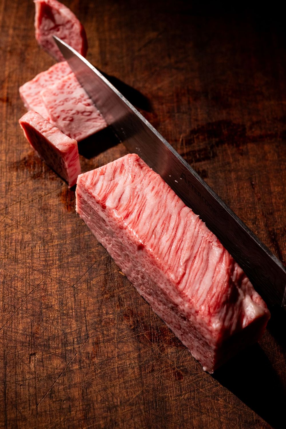 Pièce de bœuf persillée tranchée au couteau sur une planche en bois