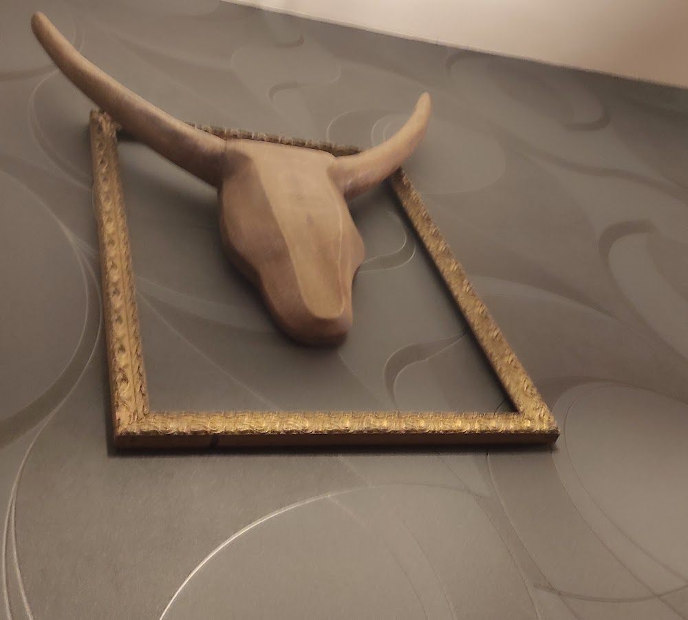 Tête de taureau en bois dans un cadre doré, sur un mur