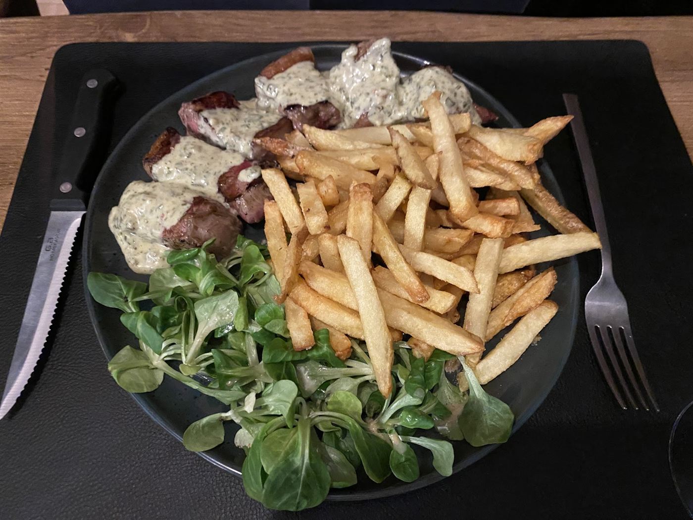 Assiette de viande nappée de sauce, frites et mâche